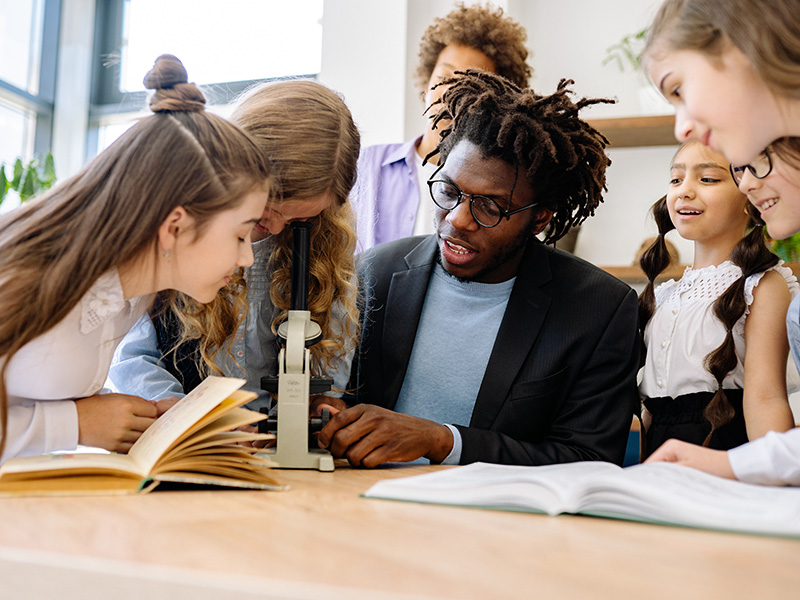 a teacher and kids looking into a microscope