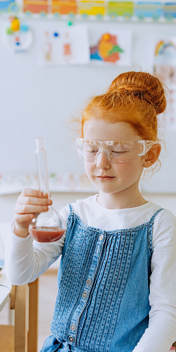 a girl holding a destillation flask,experimenting chemistry